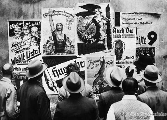 Passanten betrachten Wahlplakate verschiedener Parteien zur Reichstagswahl (14. September  1930)