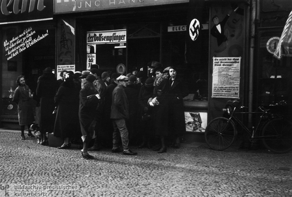 Passanten vor einem Radio-Geschäft in Berlin hören die öffentliche Rundfunk-Übertragung einer Hitlerrede (1936) 